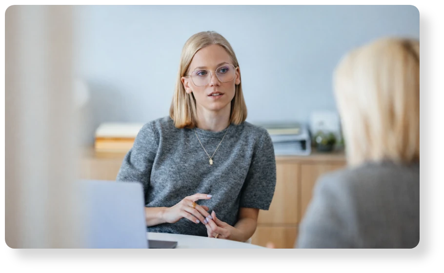Businesswoman wearing glasses speaking during a one-on-one professional meeting.