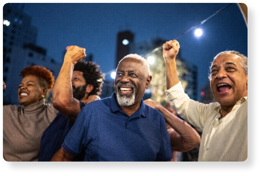 A group of colleagues celebrating together outdoors, smiling and raising their fists in excitement.
