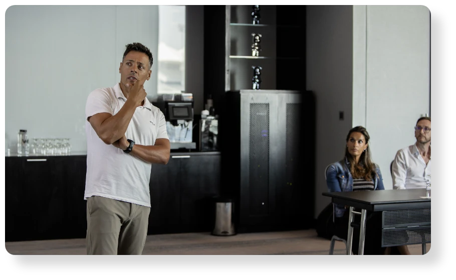Business professional presenting to colleagues during a meeting, while team members listen attentively in a modern office.