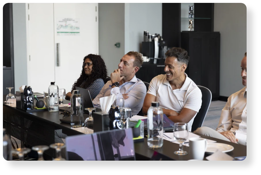 Colleagues seated around a conference table, listening and engaging during a business meeting.