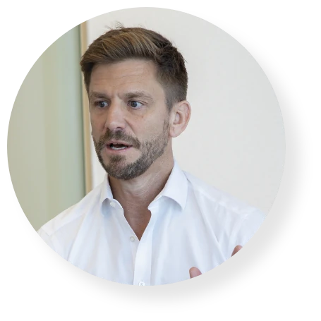 Portrait of a business professional in a white shirt speaking during an interview or presentation.